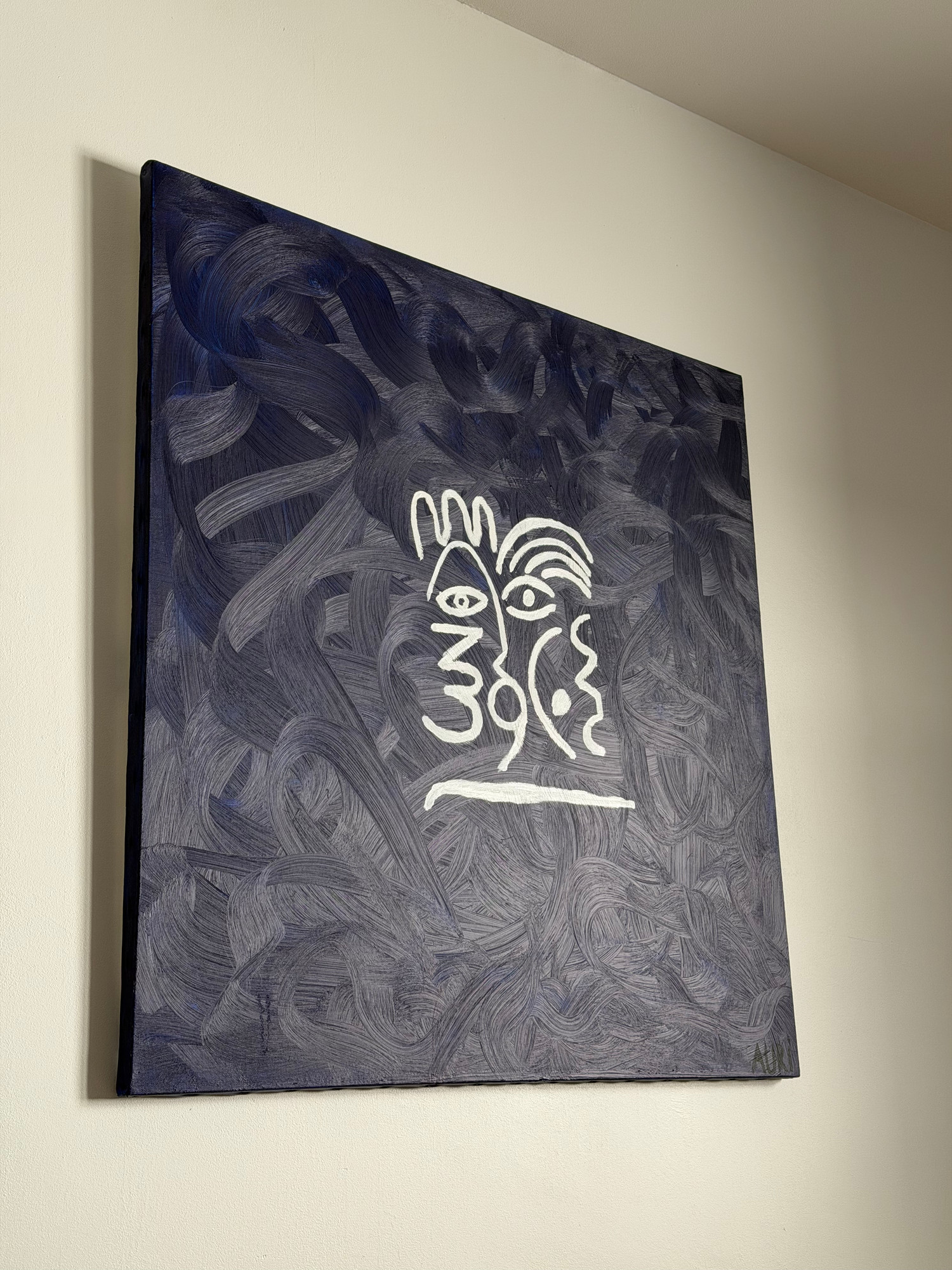 Bleu Joncols accrochée sur un mur clair, vue de trois quarts : la toile bleu nuit et son trait blanc se détachent du mur.